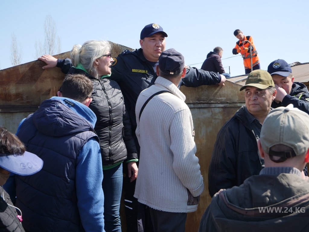 Милиционер пытается не допустить людей на крыши гаражей