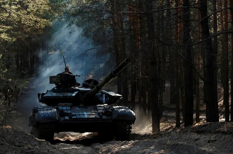 Украинские военные едут на захваченном российском танке недалеко от Купянска
