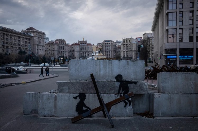Противотанковые ежи на Майдане Незалежности в Киеве. На бетонном блоке, установленном за одним из них, нарисовано граффити с детьми, качающимися на еже, как на качелях