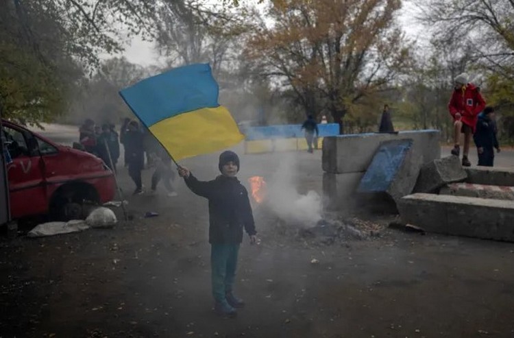 Мальчик размахивает украинским флагом на бывшем российском блокпосту на въезде в Херсон