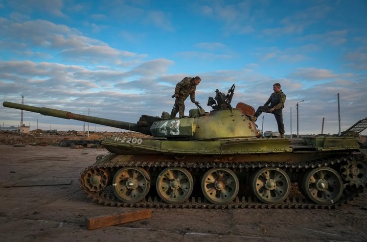 Украинские военные осматривают подбитый российский танк в селе Чернобаевка