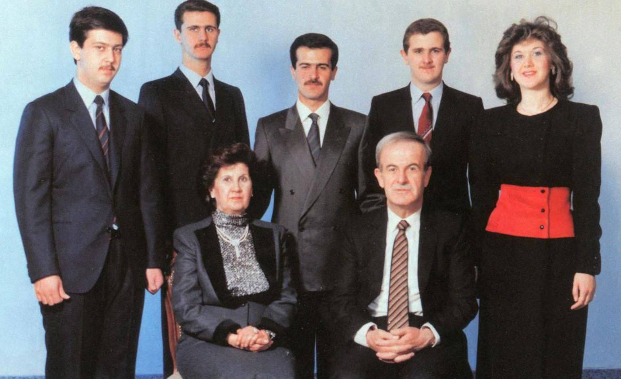 Хафез Асад (сидит справа) — бывший президент Сирии (1971-2000). Аниса Махлуф (сидит слева) — супруга Хафеза Асада и мать его детей. Башар Асад (второй слева, стоящий) — нынешний президент Сирии, сын Хафеза Асада. Басиль Асад (в центре, стоящий) — старший сын Хафеза Асада, считавшийся его наследником до своей смерти в 1994 году. Махер Асад (слева, стоящий) — младший сын Хафеза Асада, военный и командующий элитными подразделениями сирийской армии. Маджид Асад (справа от Басиля, стоящий) — младший сын Хафеза Асада, умерший в 2009 году. Бушра Асад (крайняя справа, стоящая) — единственная дочь Хафеза Асада.