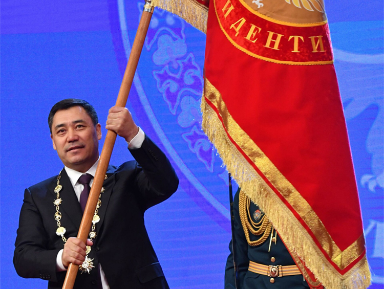 Садыр Жапаров во время инаугурации со штандартом президента