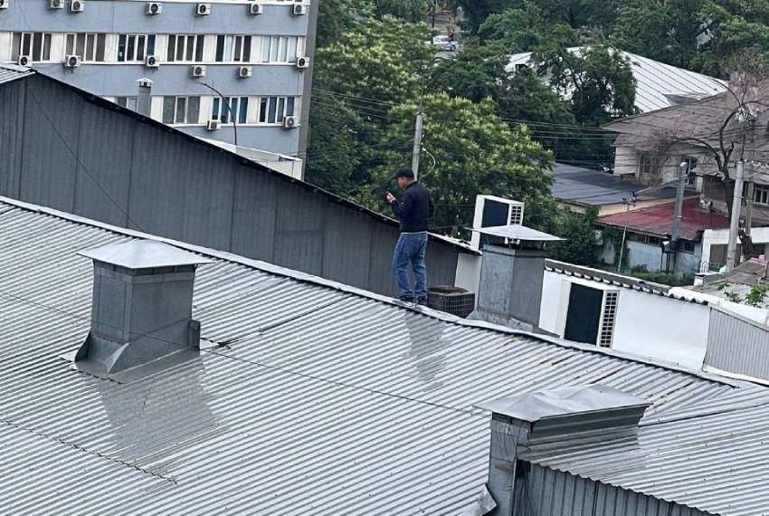 Человек идет по мокрой крыше без страховки